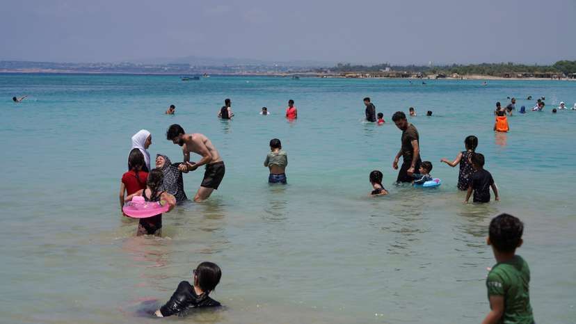 People swim at a public beach in Latakia