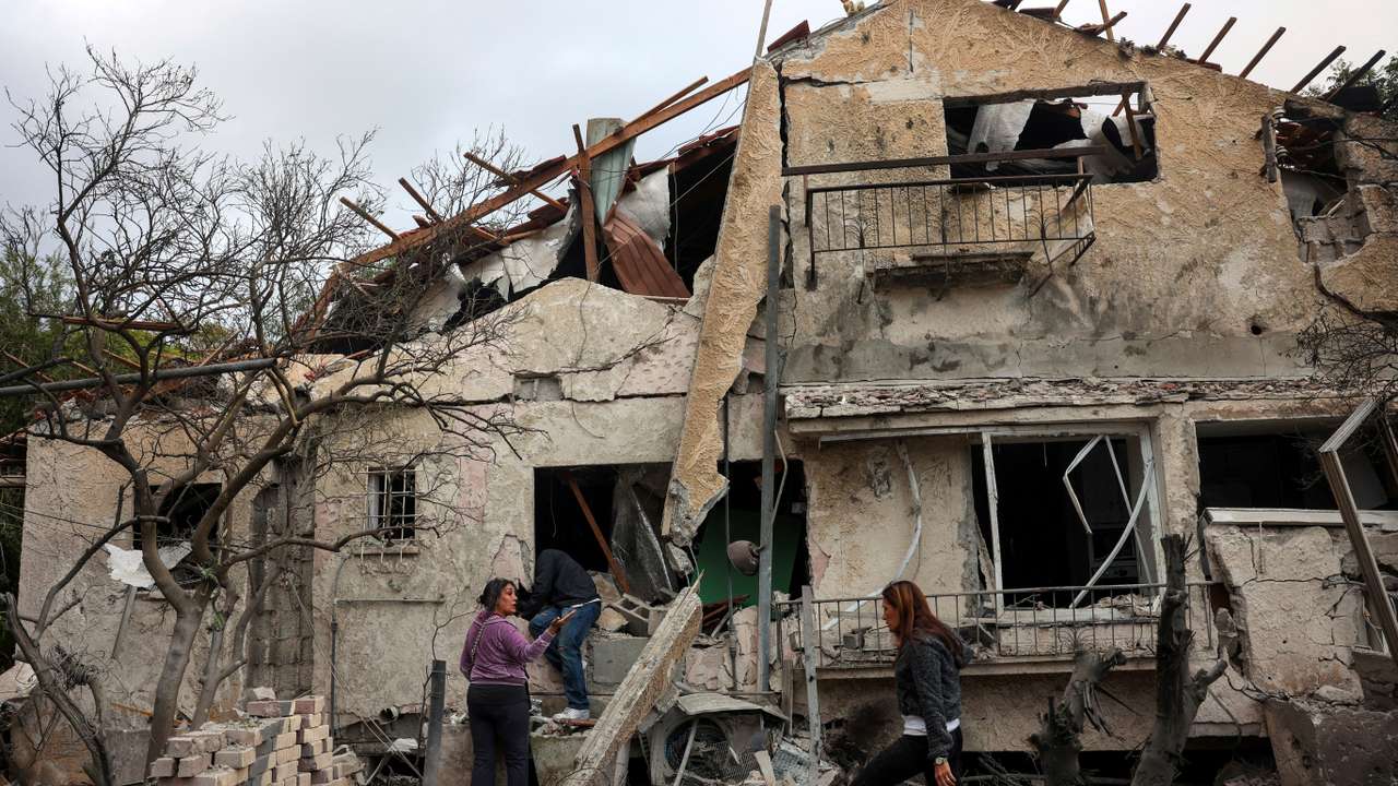 People check their family's damaged house at the scene where one of the projectiles fell, after projectiles crossed over to Israel from Lebanon, in Rinatiya