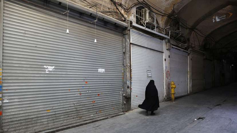 A person walks in front of closed shops in the Tehran Bazaar following the Israeli strikes on Iran, in the centre of Tehran