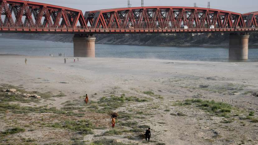 People walk on the dry riverbed of the Indus River in Hyderabad, Pakistan