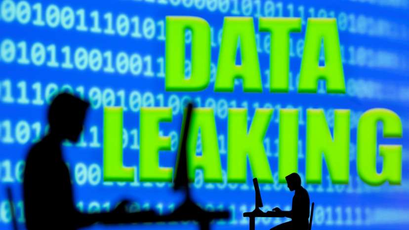 A 3D printed model of men working on computers are seen in front of displayed binary code and words "Data leaking
