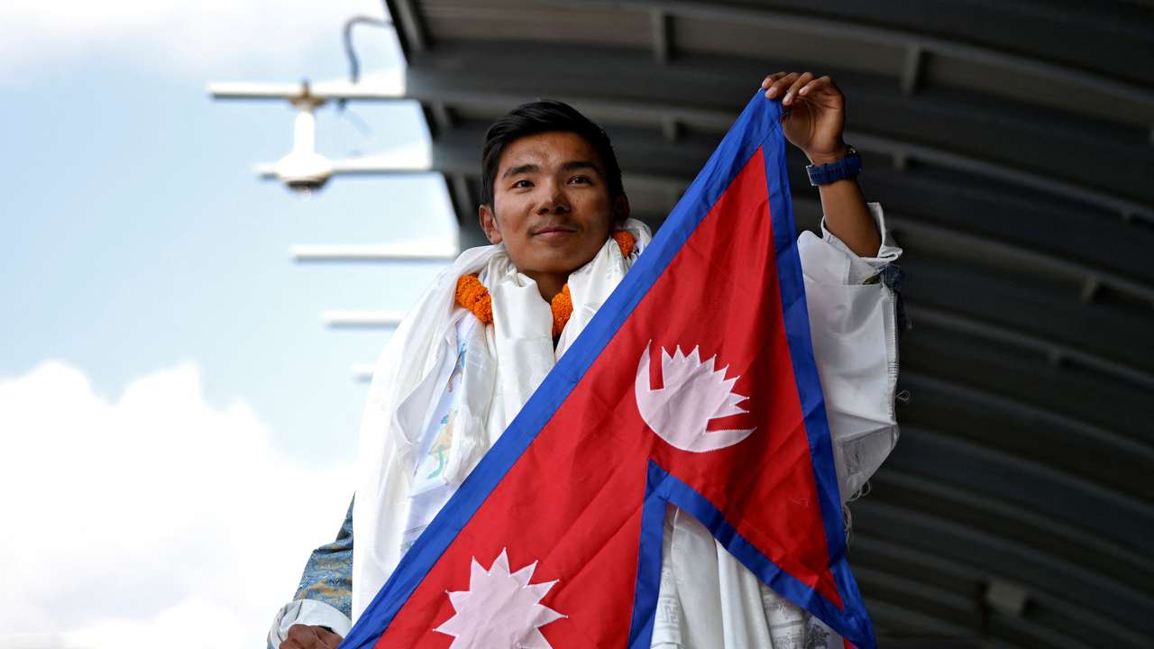 Nima Rinji Sherpa holds a national flag upon his arrival at the airport during a welcoming ceremony in Kathmandu