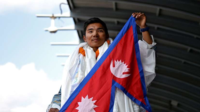Nima Rinji Sherpa holds a national flag upon his arrival at the airport during a welcoming ceremony in Kathmandu