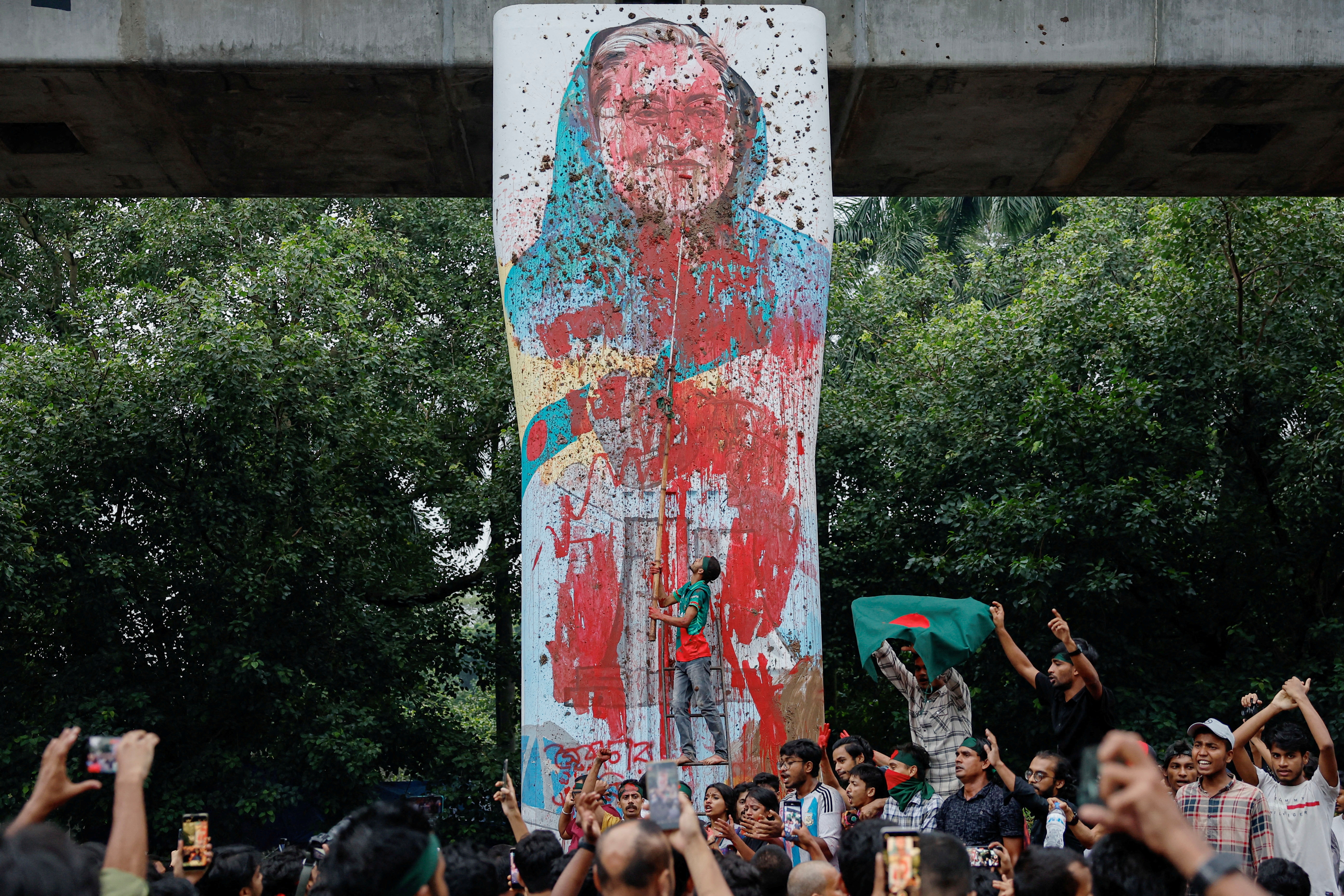FILE PHOTO: Protesters shout slogans as they vandalise a mural of Bangladeshi PM Hasina with paint and mud, demanding her resignation at TSC area of University of Dhaka