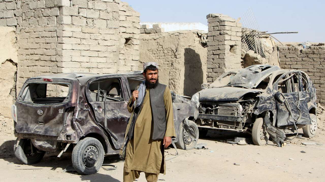 A Taliban fighter stands next to vehicles destroyed during an airstrike following a temporary ceasefire amid the conflict between Afghanistan and Pakistan, in Spin Boldak