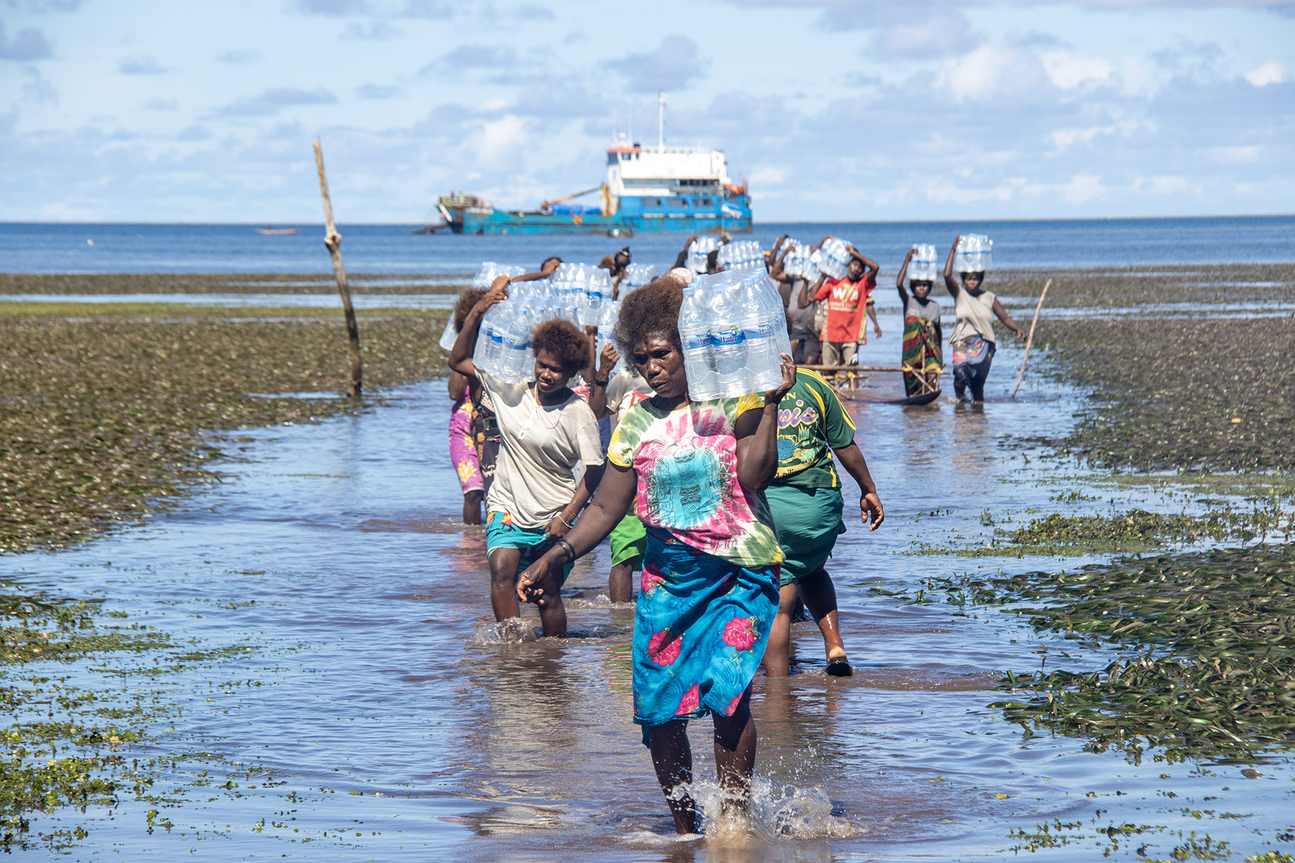 A supplied image obtained on Thursday, July 3, 2025, of women moving relief water from the charted vessel to shore at Mantoia Village on Pinapel Island in the Atolls District in northern Bougainville, Papua New Guinea. (AAP Image/Supplied by CARE Papua New Guinea, Benson Wanguare)