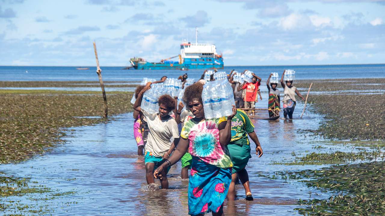 A supplied image obtained on Thursday, July 3, 2025, of women moving relief water from the charted vessel to shore at Mantoia Village on Pinapel Island in the Atolls District in northern Bougainville, Papua New Guinea. (AAP Image/Supplied by CARE Papua New Guinea, Benson Wanguare)