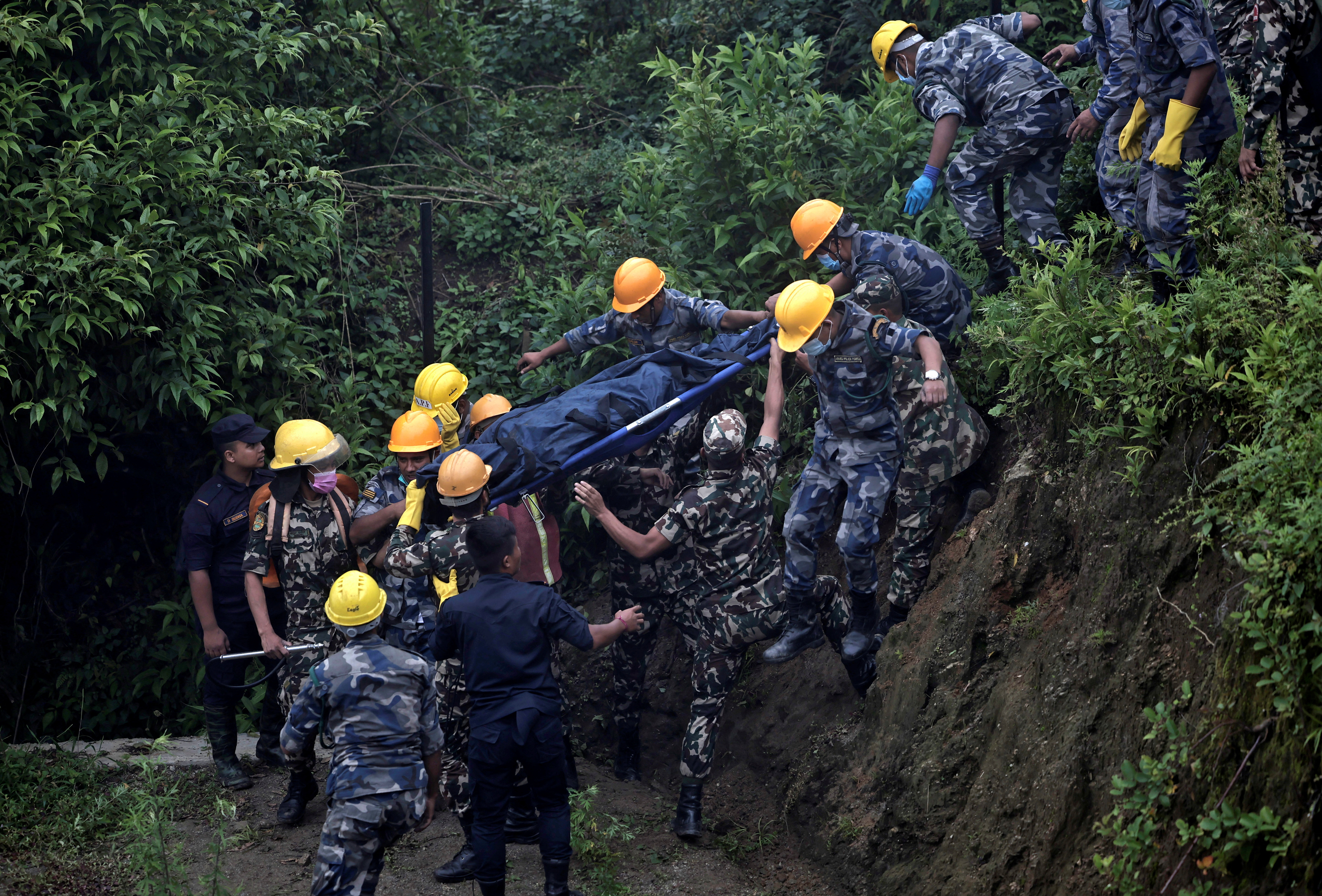 Security force personnel carry the body of a victim at the site of a helicopter crash on the outskirts of Kathmandu