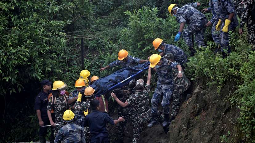 Security force personnel carry the body of a victim at the site of a helicopter crash on the outskirts of Kathmandu