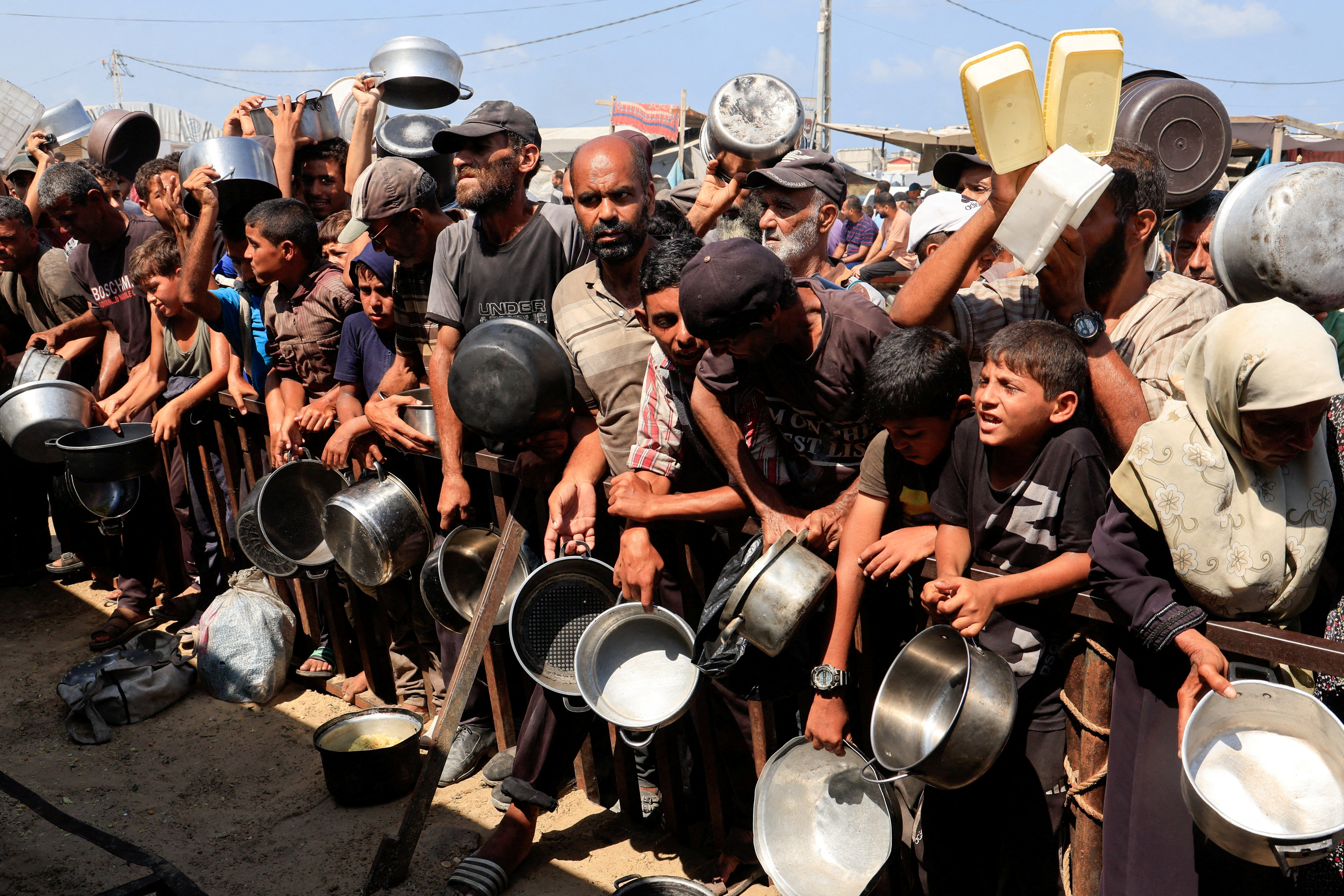 FILE PHOTO: Palestinians wait to receive food from charity kitchen in Khan Younis