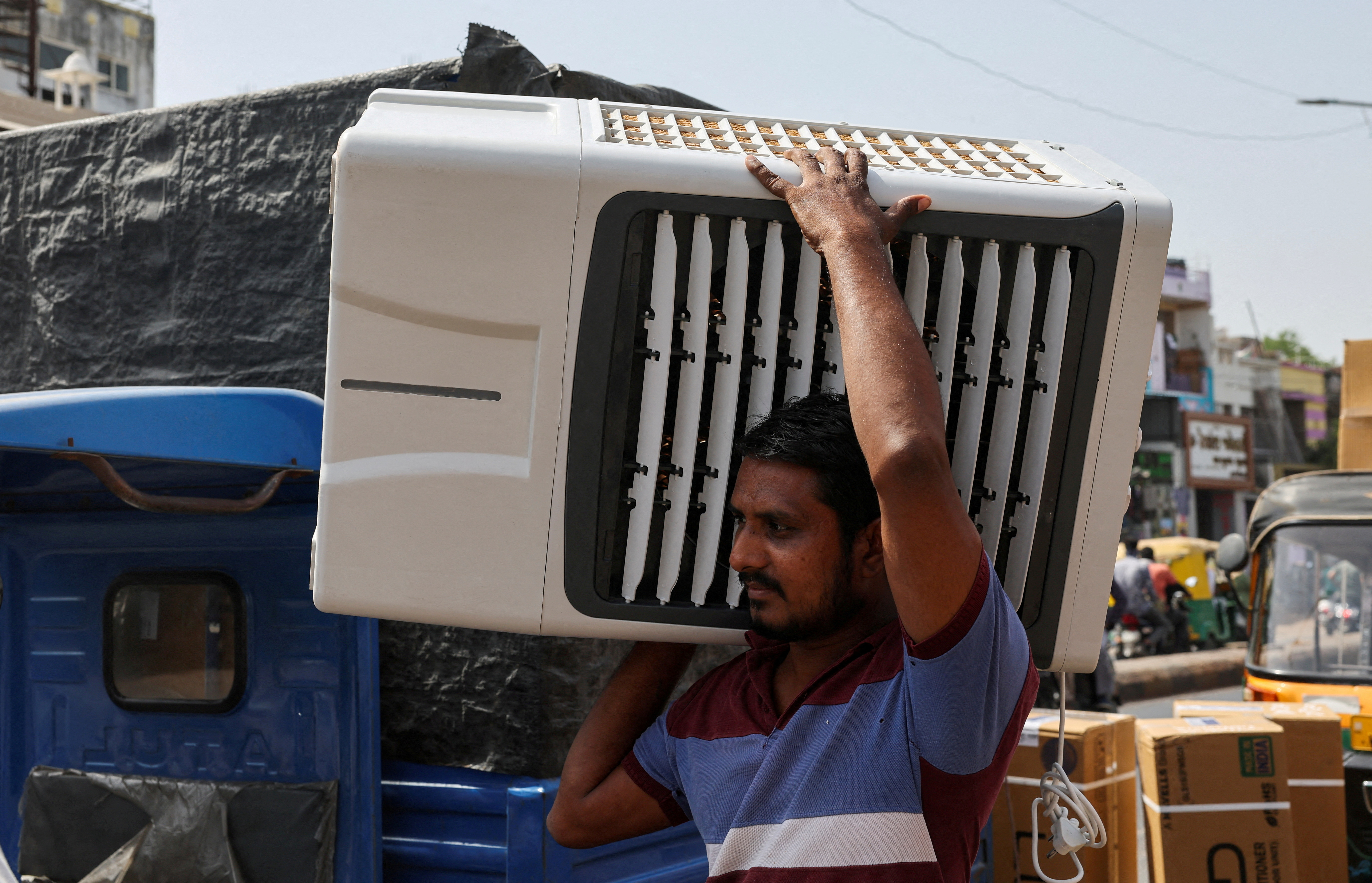 FILE PHOTO: FILE PHOTO: A worker carries an air cooler for delivery to a customer during the heat wave in Ahmedabad
