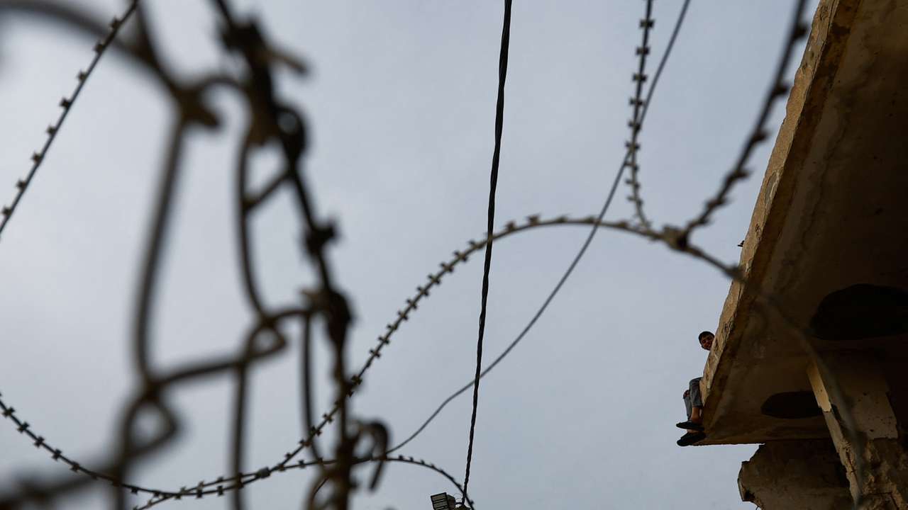 A child sits on a building near the Rafah border, as Hamas militants are expected to release hostages