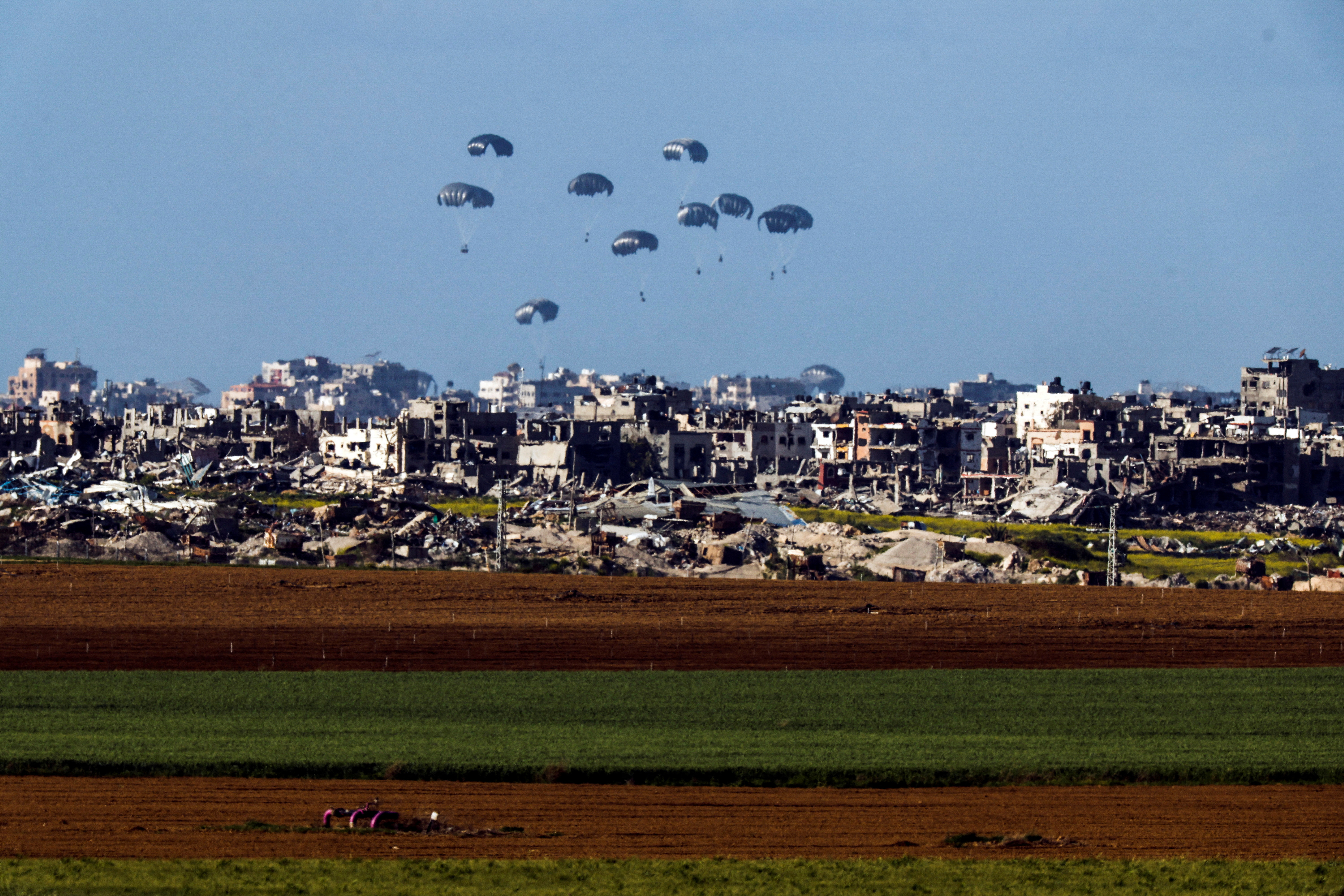 FILE PHOTO: Packages dropped from a military aircraft fall towards northern Gaza, as seen from Israel
