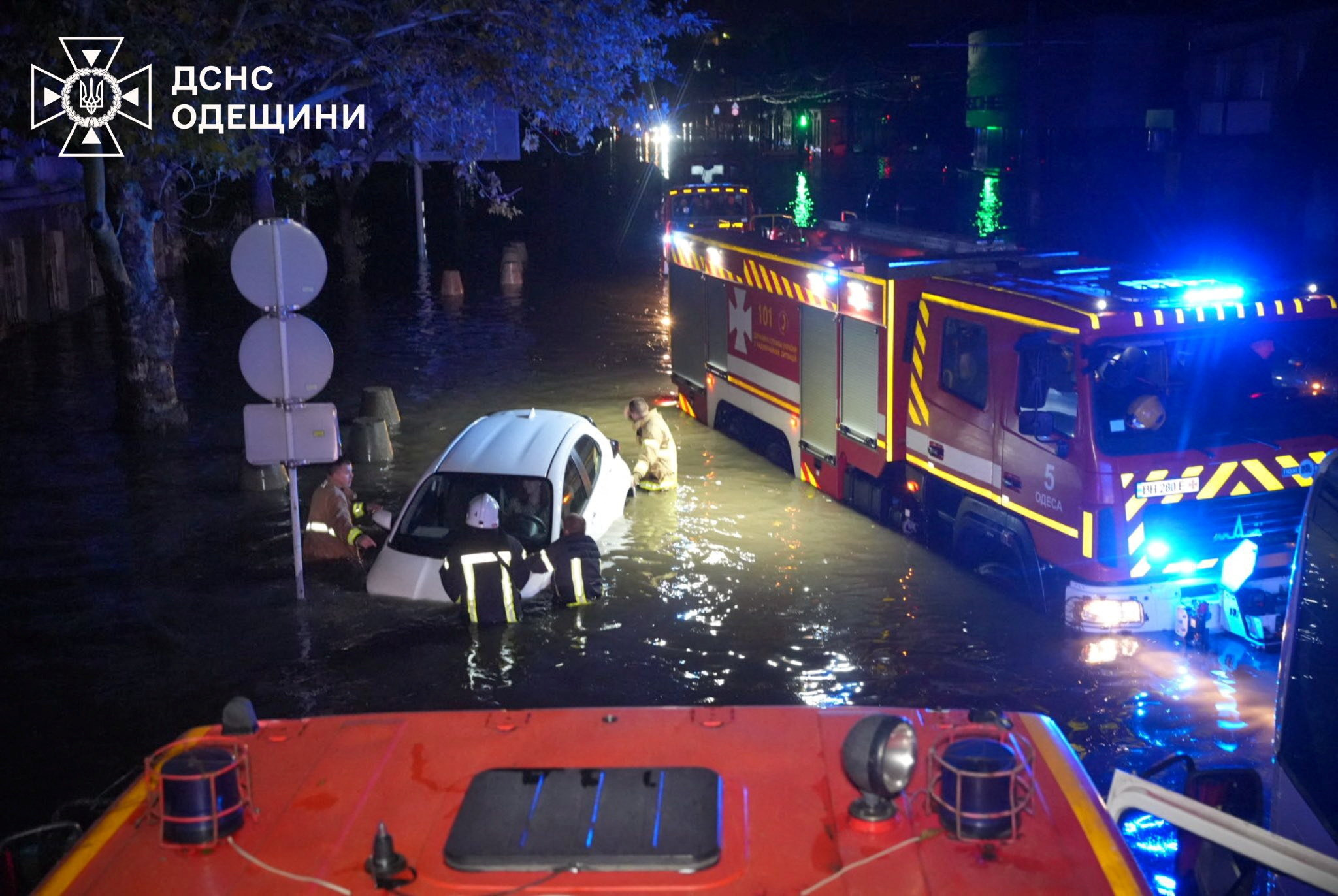 Rescuers push a partially submerged car on a flooded street in Odesa