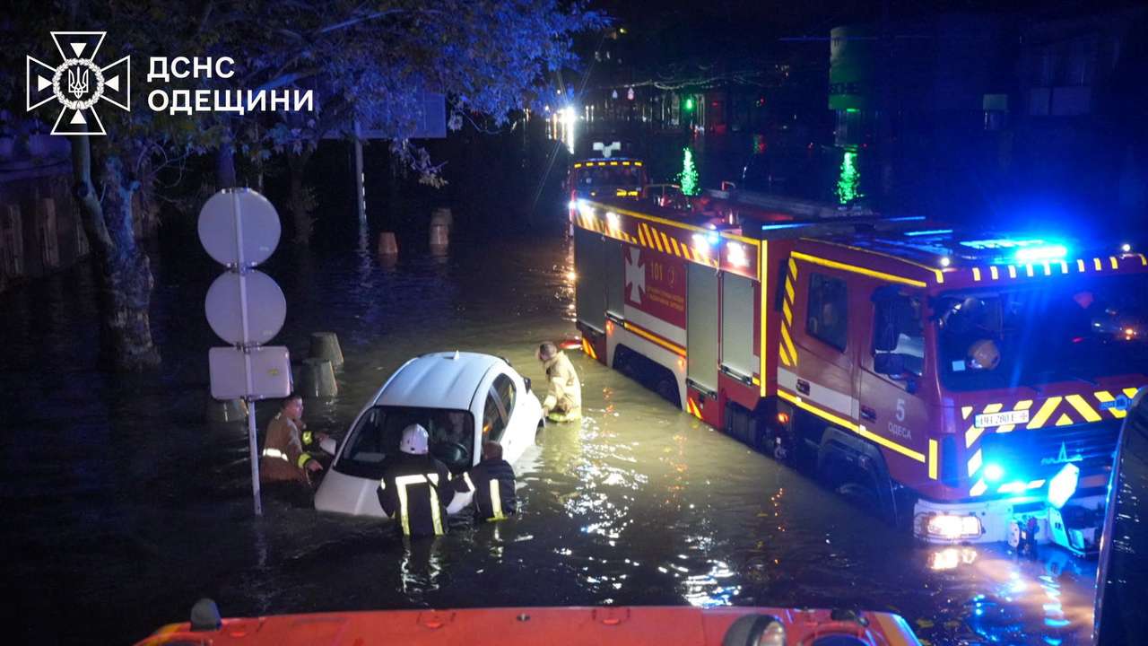 Rescuers push a partially submerged car on a flooded street in Odesa