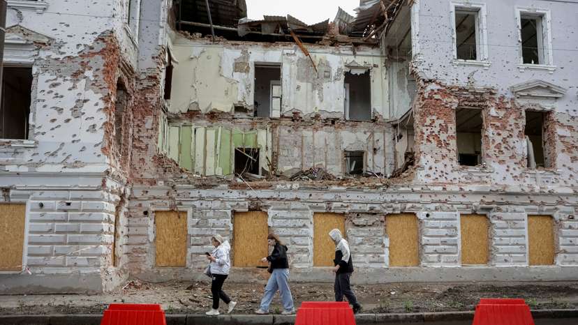 Residents walk at a street near a building damaged by Russian missile strikes in Sumy