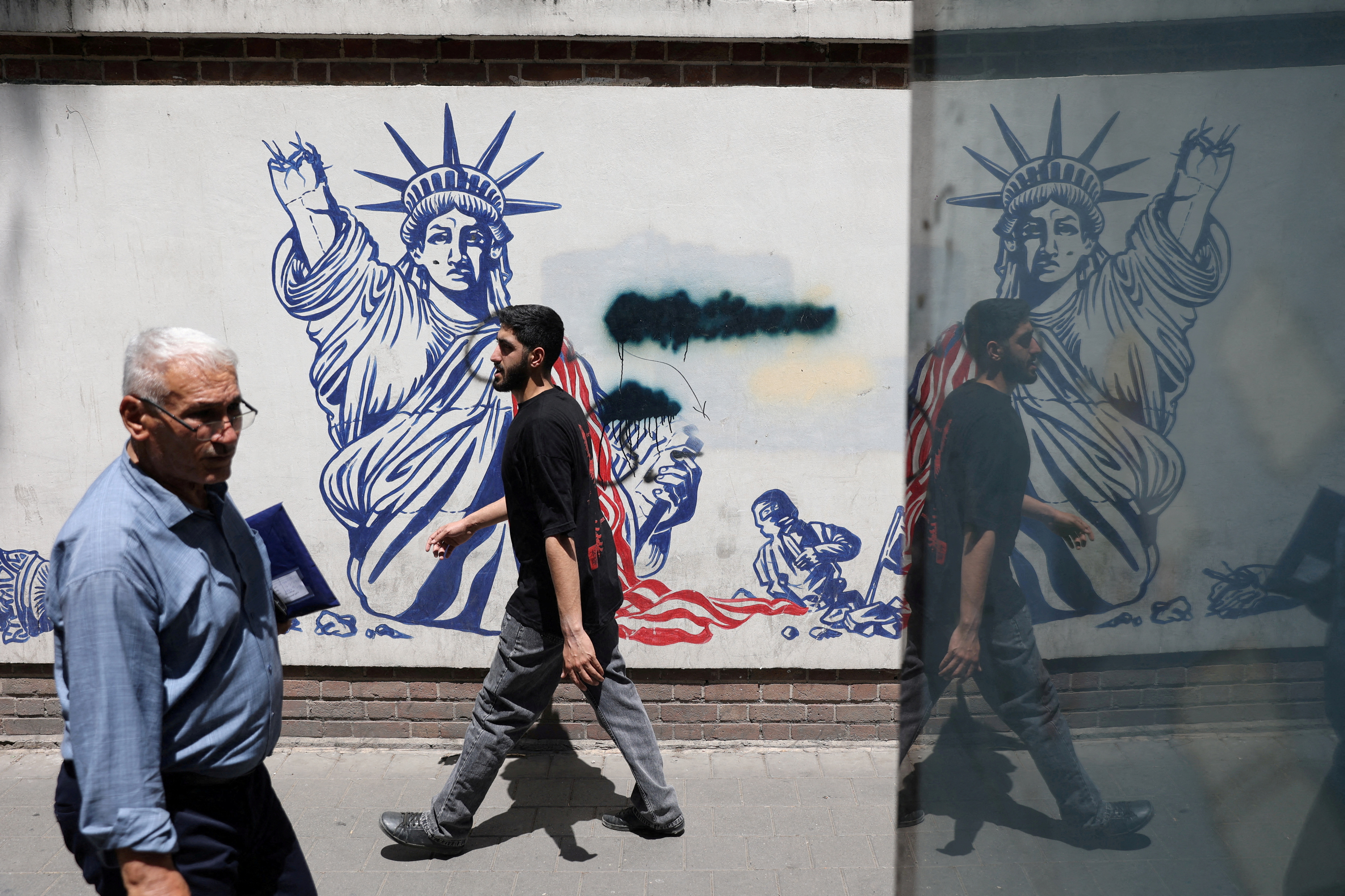 FILE PHOTO: People walk past an anti-U.S. mural on a street in Tehran