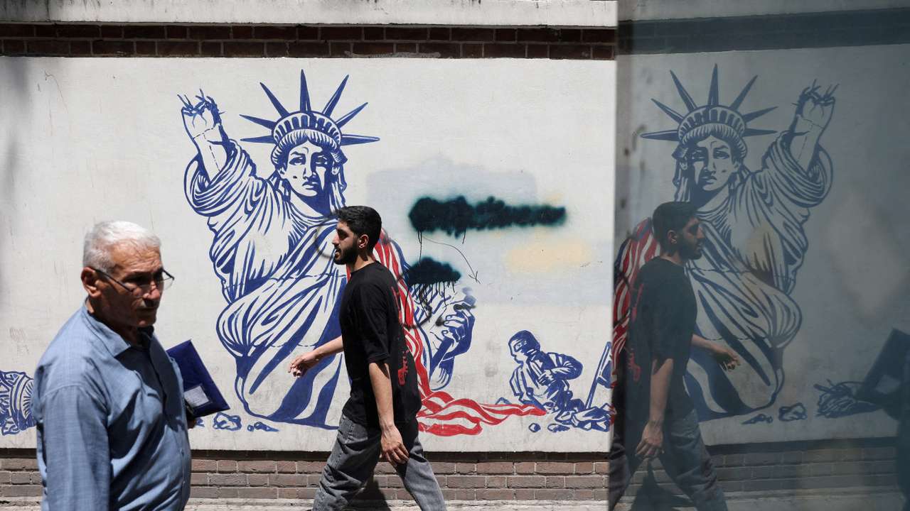 FILE PHOTO: People walk past an anti-U.S. mural on a street in Tehran