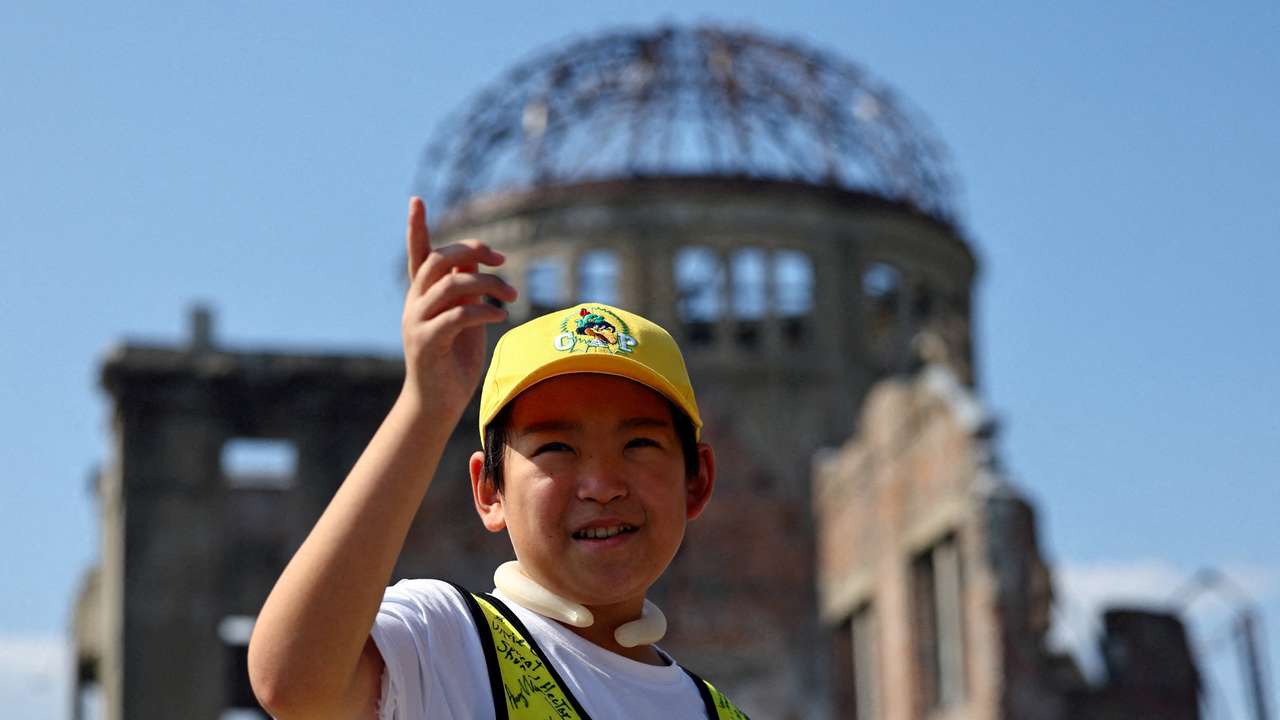 Shun Sasaki, an elementary school student in Hiroshima, guides foreign visitors in front of the Atomic Bomb Dome in Hiroshima