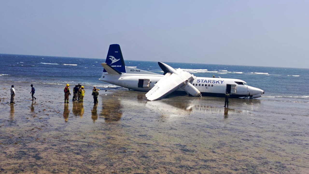 Rescuers stand near a plane that crashed on the seashore in Mogadishu