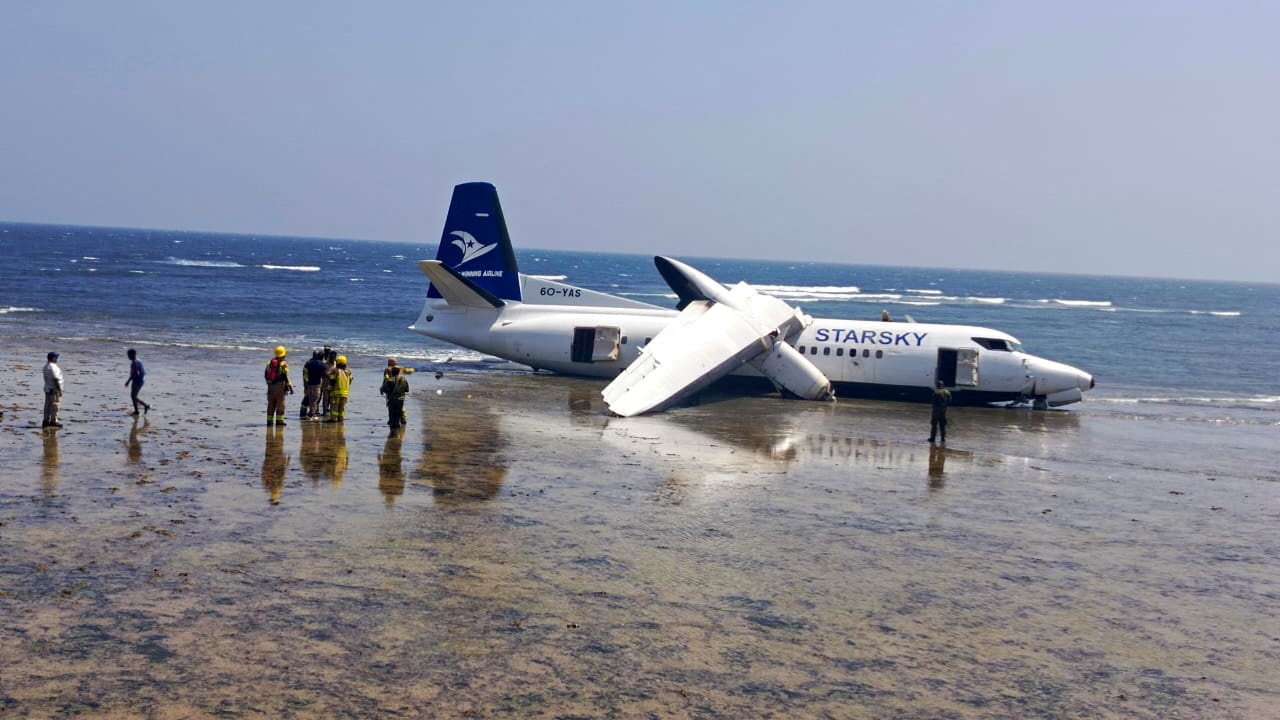 Rescuers stand near a plane that crashed on the seashore in Mogadishu