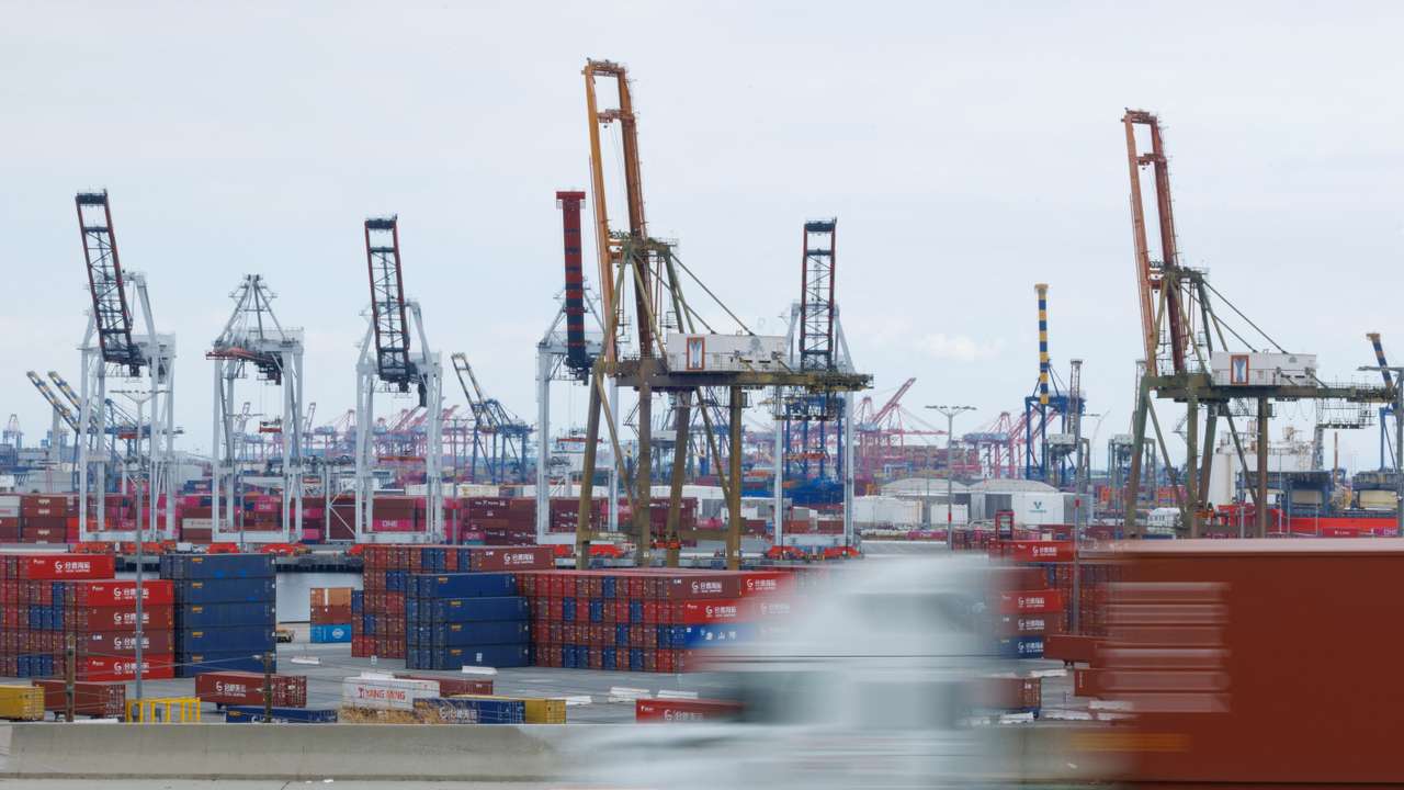 Semi-truck drives past Chinese shipping containers at the Port of Los Angeles
