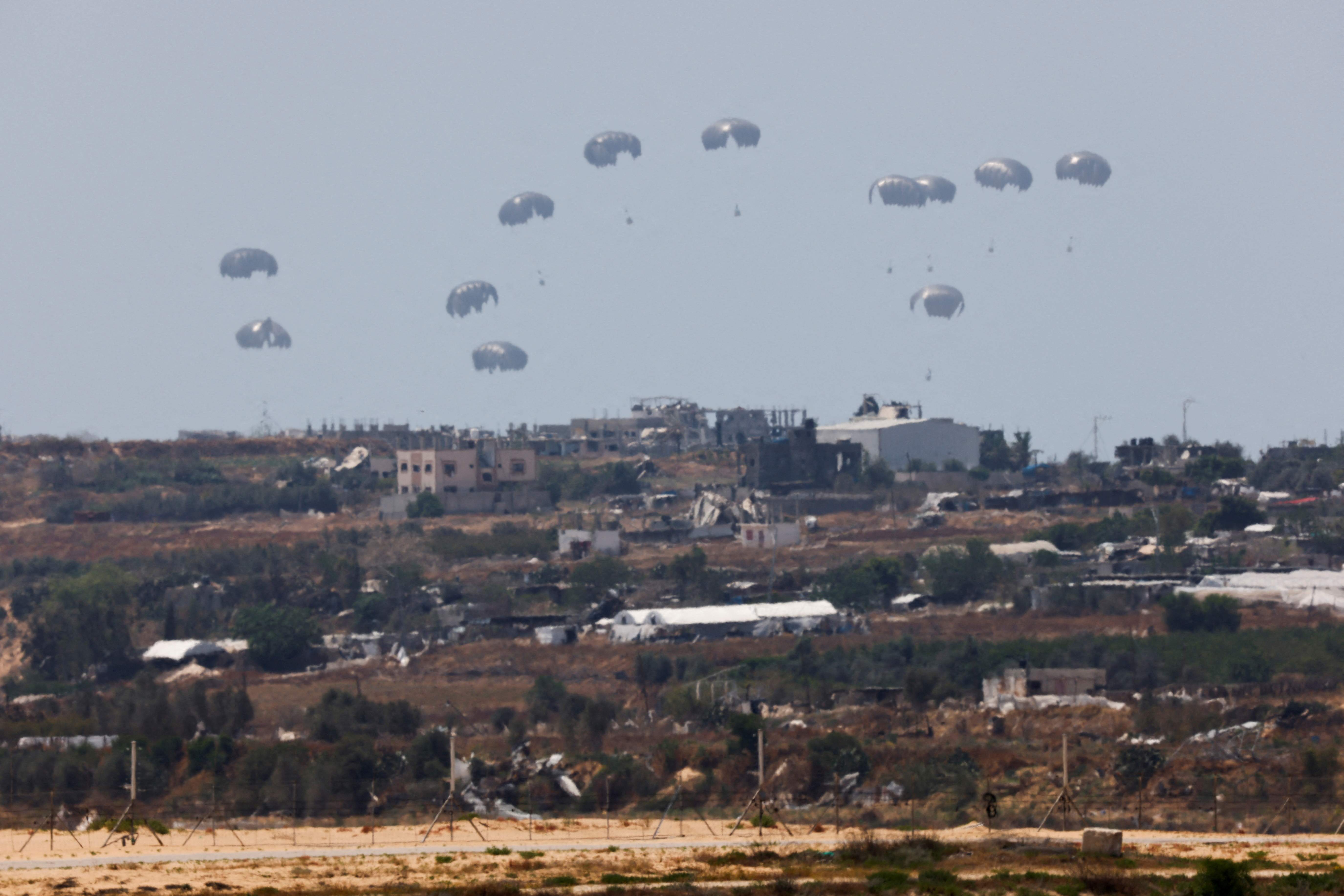 Humanitarian aid falls through the sky towards the Gaza Strip