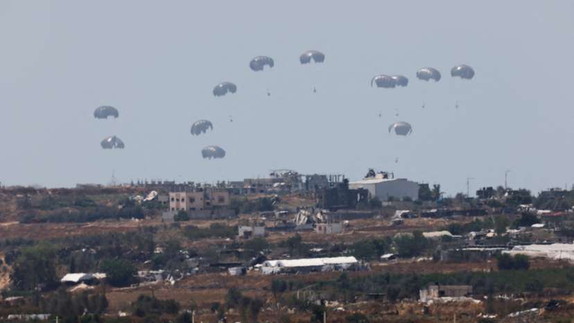 Humanitarian aid falls through the sky towards the Gaza Strip