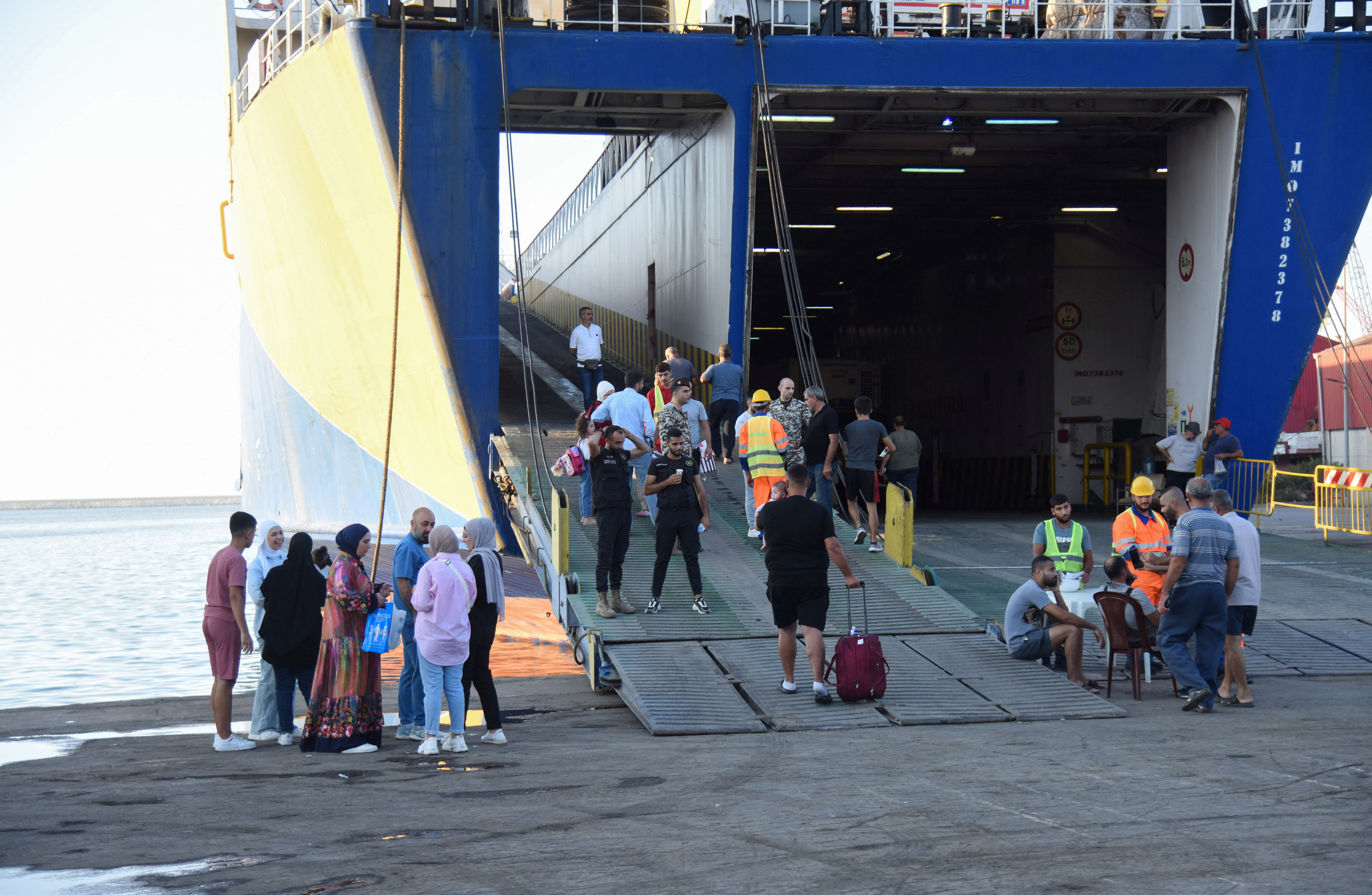 People wait at the port to board a ferry heading to Turkey, in Tripoli