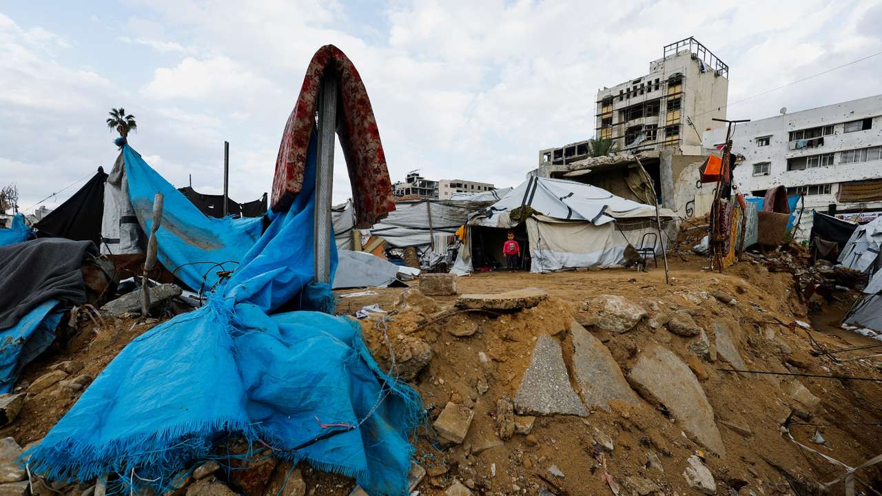 Palestinian child stands in front of a tent on a rainy day in Gaza City