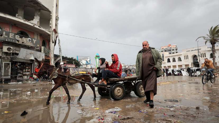 Palestinians make their way along a road on a rainy day, amid a ceasefire between Israel and Hamas, in Gaza City