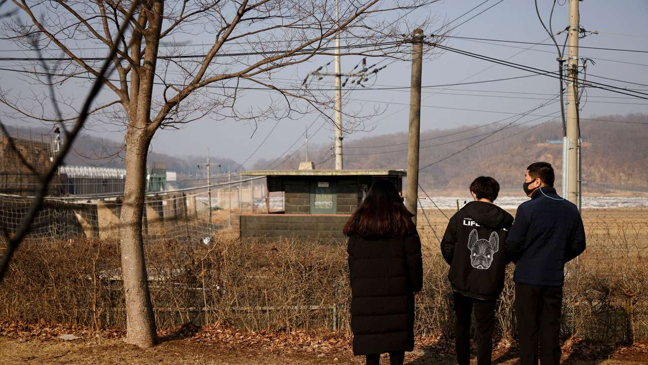 FILE PHOTO: A North Korean defector and his children stand in front of a barbed wire fence near the demilitarised zone separating the two Koreas, in Paju