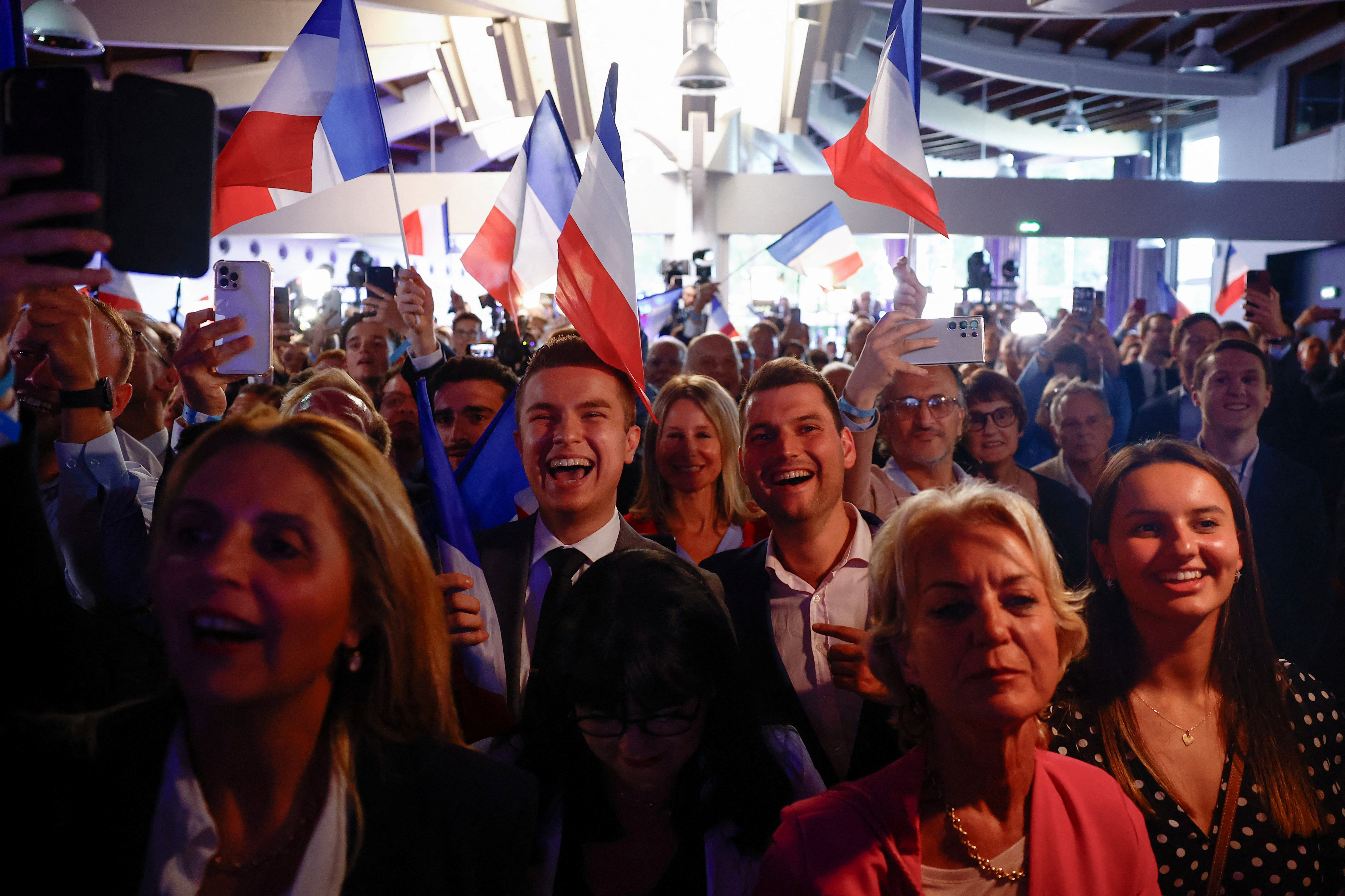 Far-right National Rally (Rassemblement National - RN) party members react after the polls closed during the European Parliament elections, in Paris