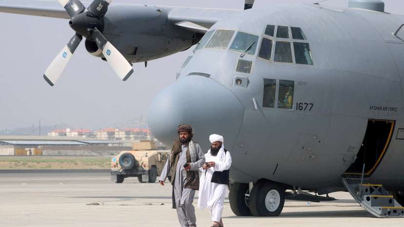 FILE PHOTO: Taliban walk in front of a military airplane a day after the U.S. troops withdrawal from Hamid Karzai International Airport in Kabul