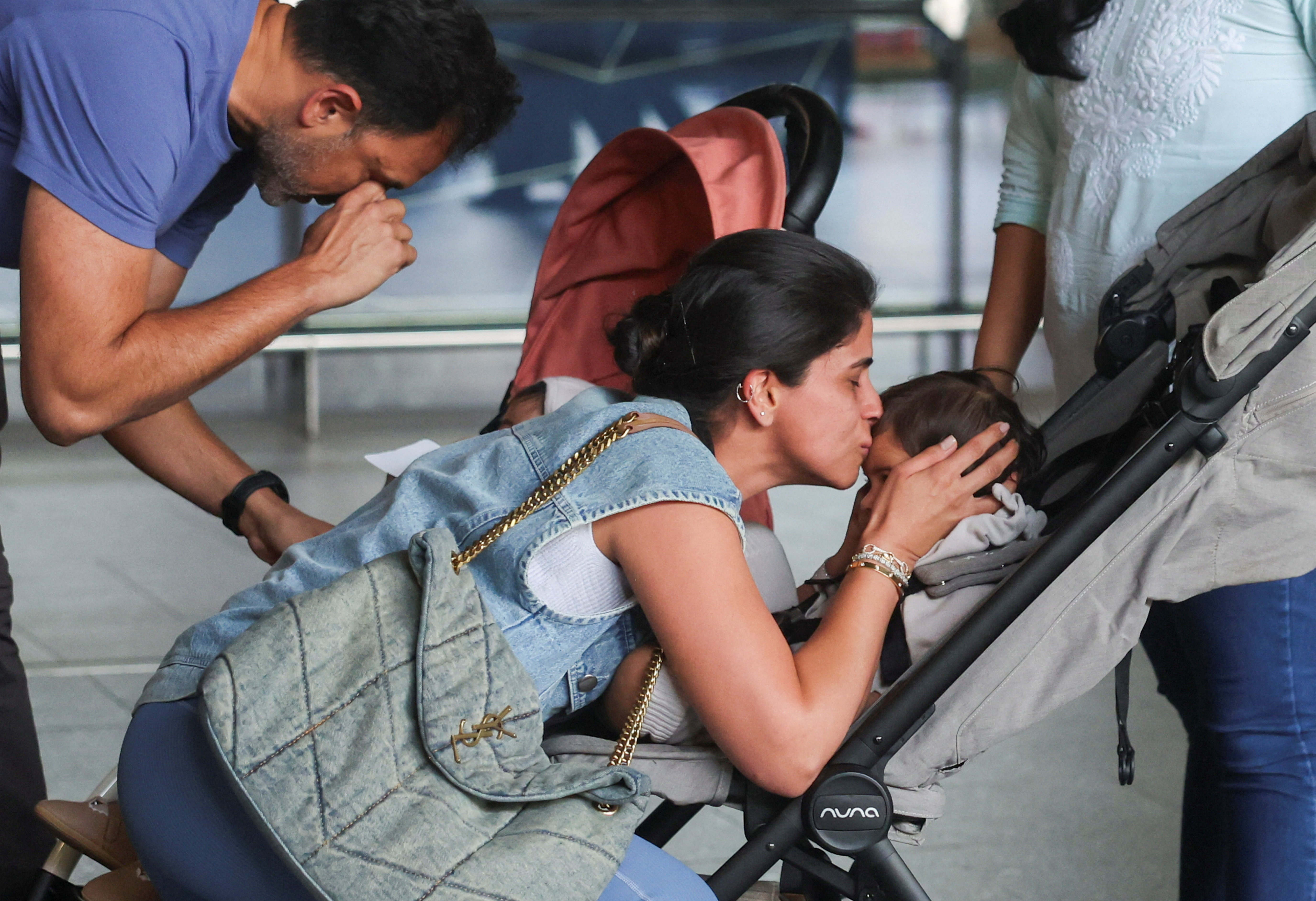 A mother kisses her child after they returned from Dubai amid the U.S.-Israel conflict with Iran, at the Chhatrapati Shivaji Maharaj International Airport in Mumbai