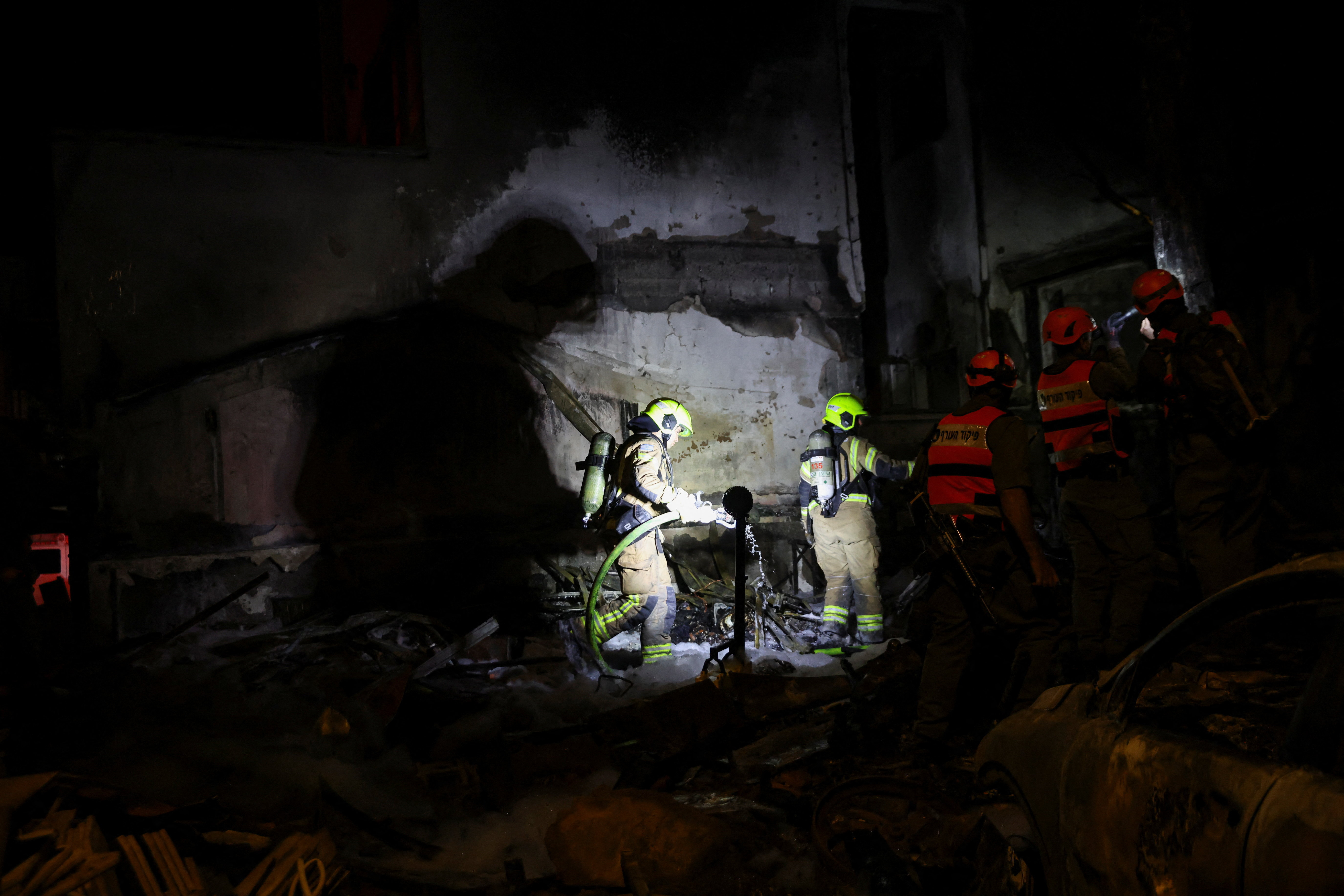 Firefighters work at the scene of a Hezbollah rocket attack on a residential building in Nahariya