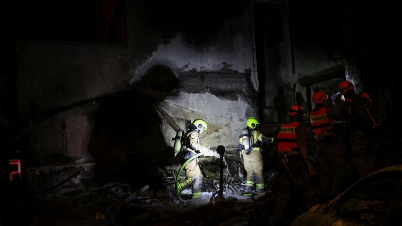 Firefighters work at the scene of a Hezbollah rocket attack on a residential building in Nahariya