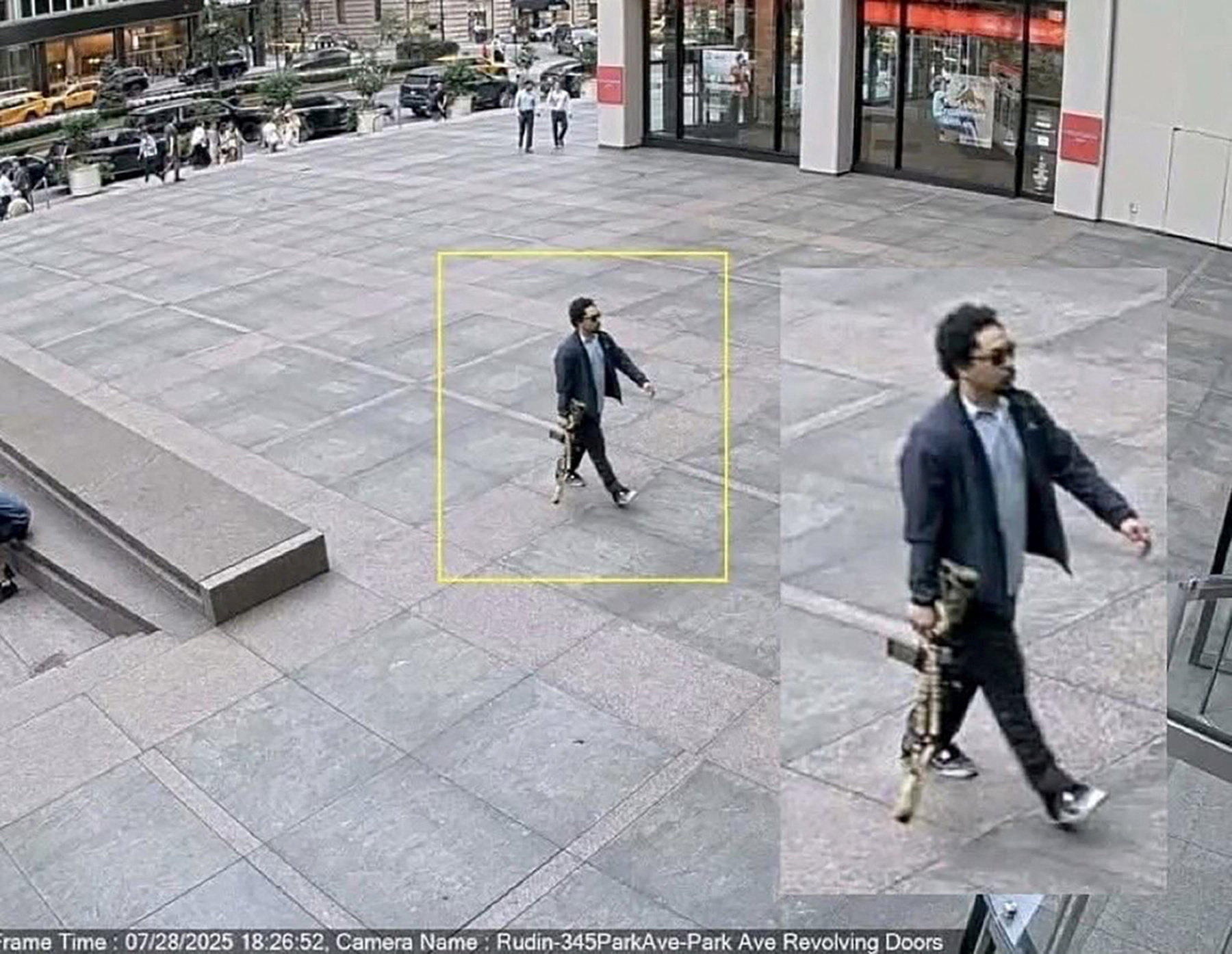 A man holding a rifle walks into an office building shortly before a shooting that killed several people in Manhattan
