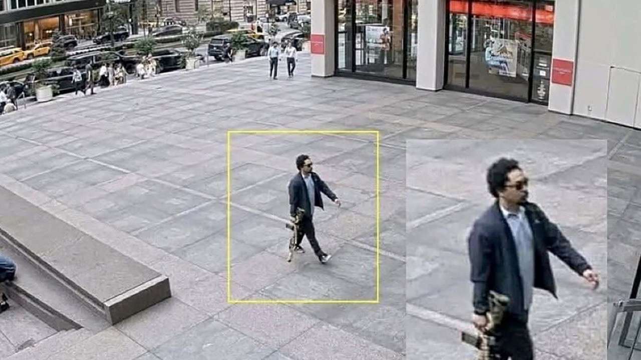 A man holding a rifle walks into an office building shortly before a shooting that killed several people in Manhattan