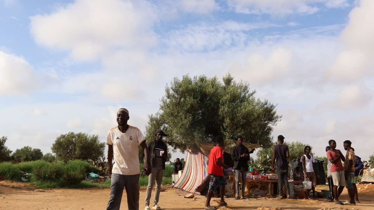 Sub-Saharan African migrants gather in a field, in El Hencha, Sfax
