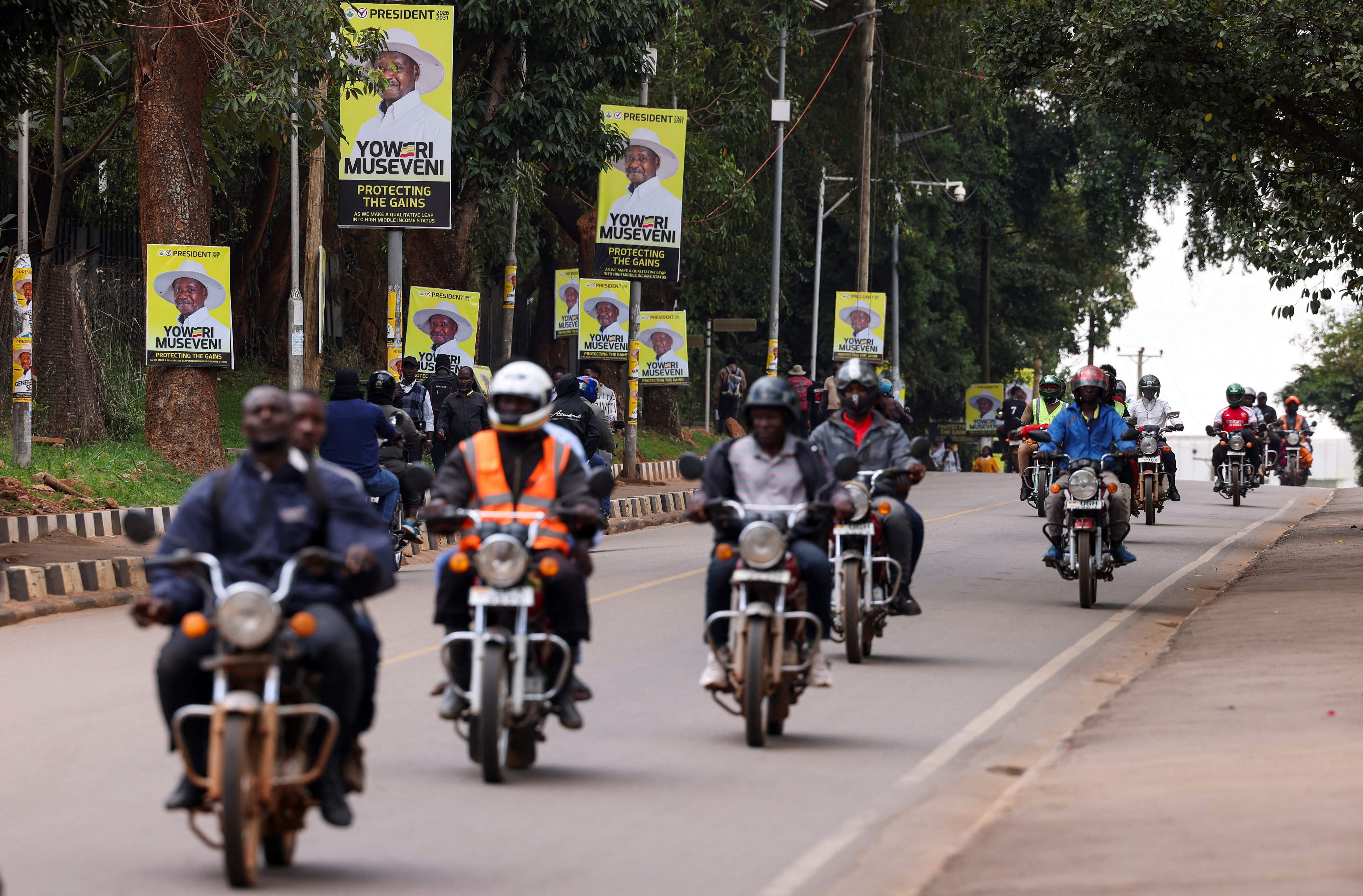 Motorcycle taxis ride past campaign posters of Uganda's President Yoweri Museveni ahead of the upcoming general election in Kampala