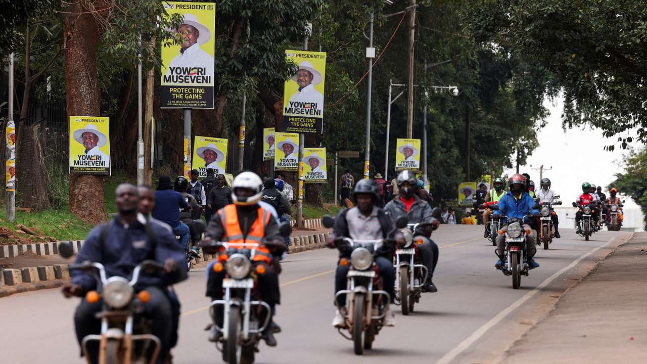 Motorcycle taxis ride past campaign posters of Uganda's President Yoweri Museveni ahead of the upcoming general election in Kampala