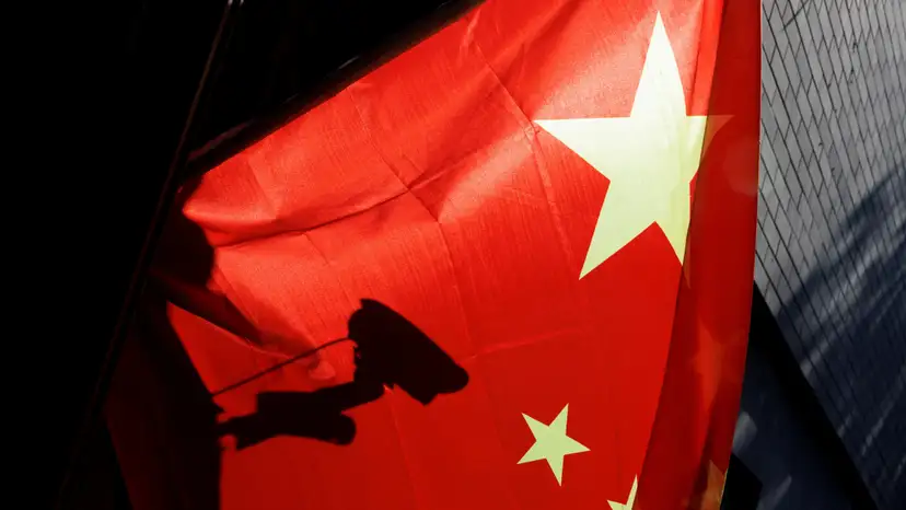 FILE PHOTO: A surveillance camera is silhouetted behind a Chinese national flag in Beijing