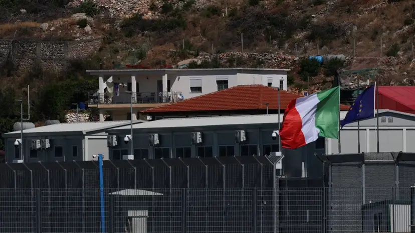FILE PHOTO: Italian and European Union flags flutter at a reception camp to process migrants rescued at sea, in Shengjin