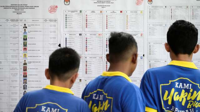 Prisoners check the list of presidential and legislative candidates at a special prison polling station in Banda Aceh