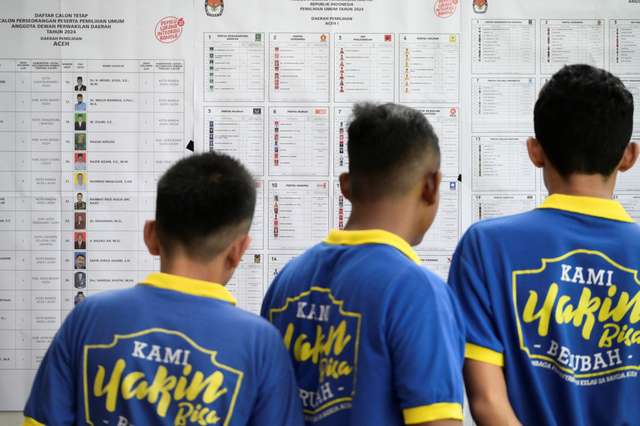 Prisoners check the list of presidential and legislative candidates at a special prison polling station in Banda Aceh