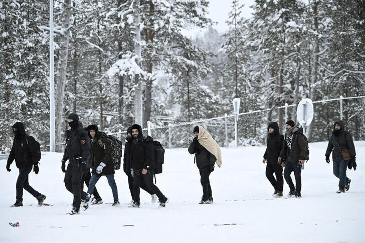 Finnish Border Guards escort migrants arriving at Raja-Jooseppi international border crossing station in Inari
