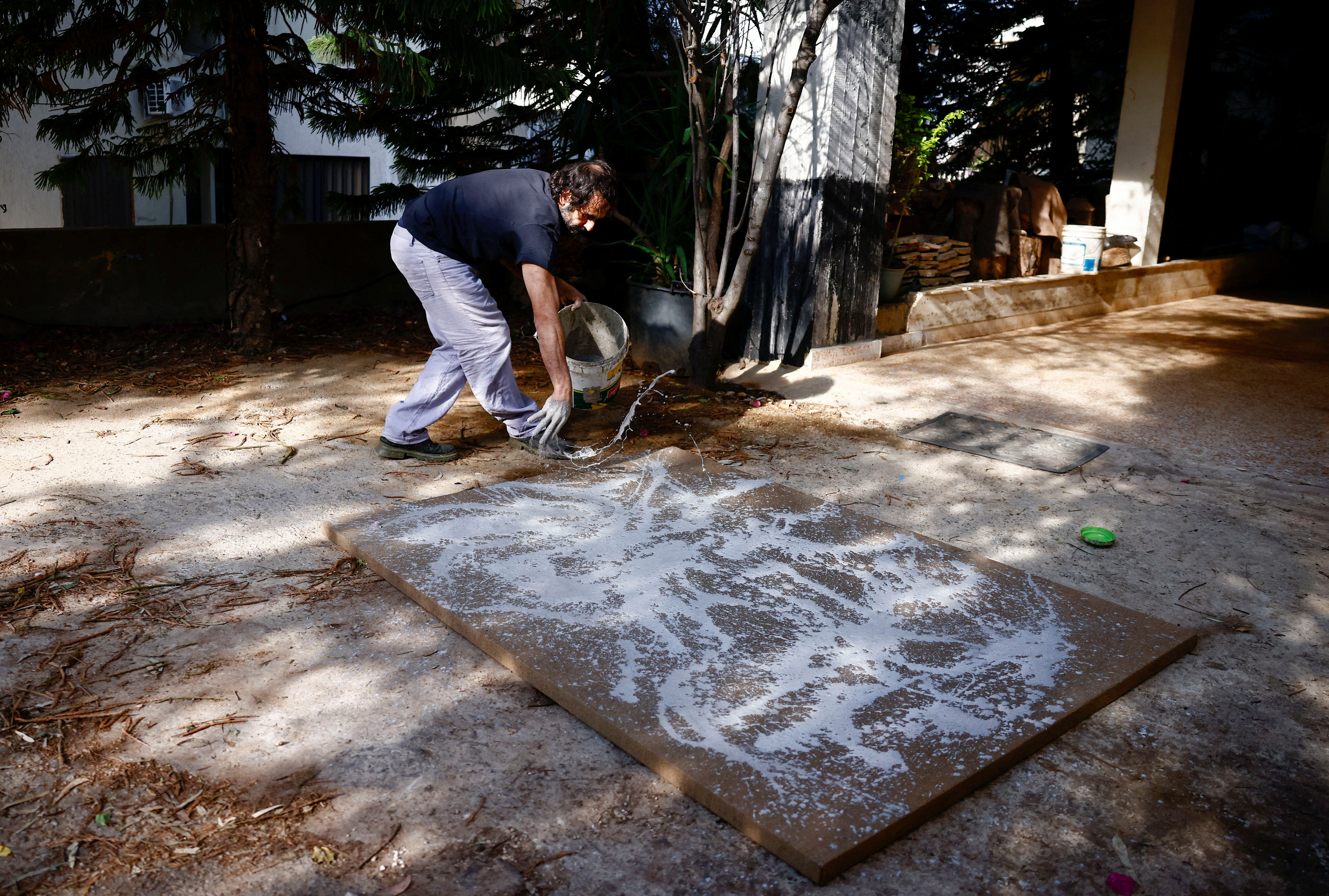 Lebanese artist Charbel Samuel Aoun works on an art piece using dust mixed with resin, in Fanar