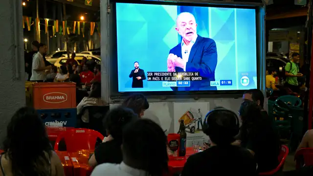 Eleitores acompanham último debate entre o presidente Luiz INácio Lula da Silva e Flavio Bolsonaro, em 23 de outubro de 2026. (Foto de Evaristo Sa / AFP)