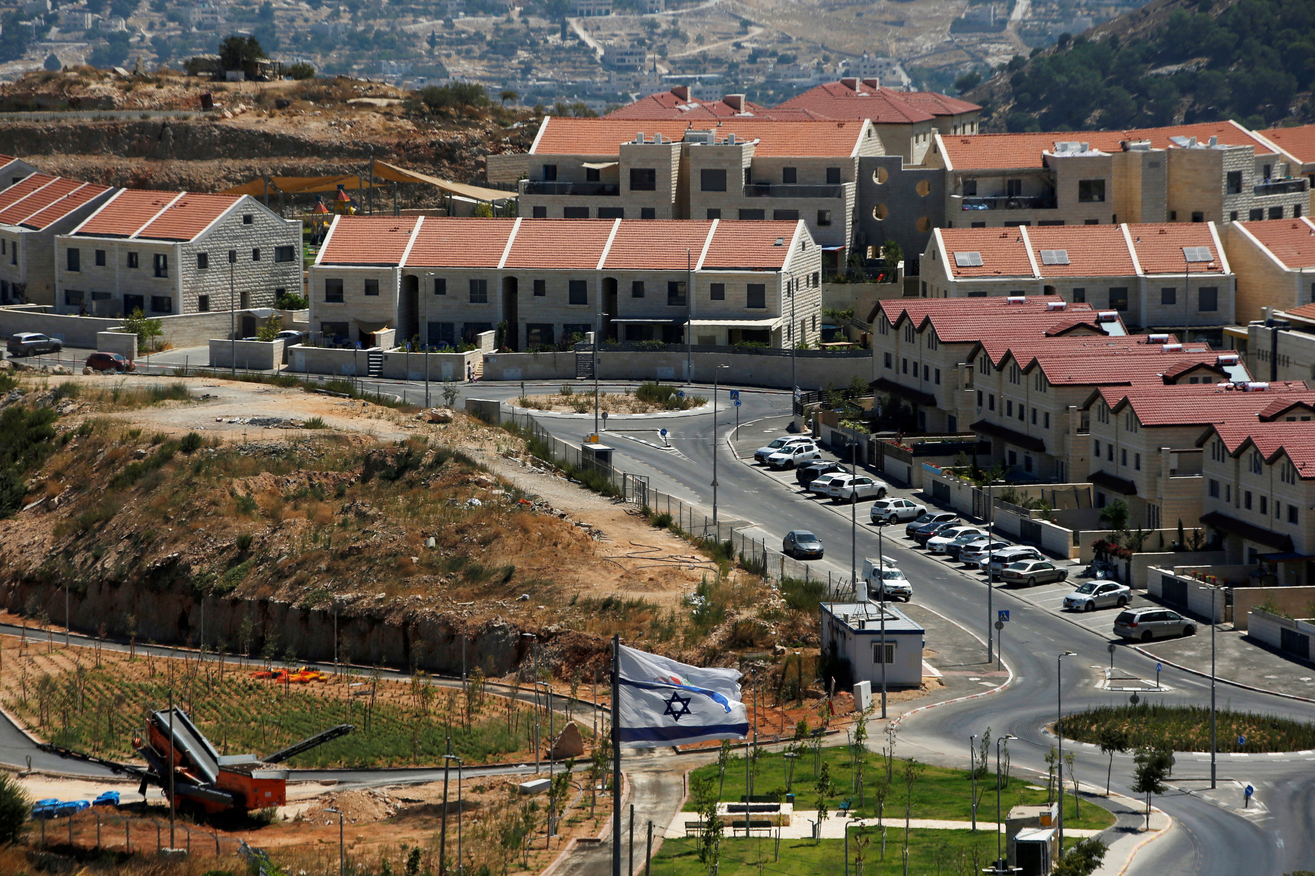 FILE PHOTO: The Israeli national flag flutters as apartments are seen in the background in the Israeli settlement of Efrat in the Israeli-occupied West Bank